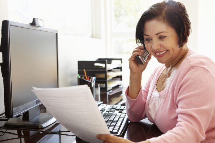 Smiling woman on the phone while looking at some documents.